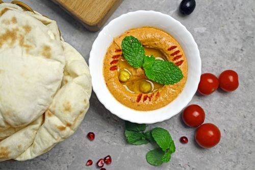 Free Delicious hummus garnished with mint leaves, served with fresh bread and cherry tomatoes. Stock Photo