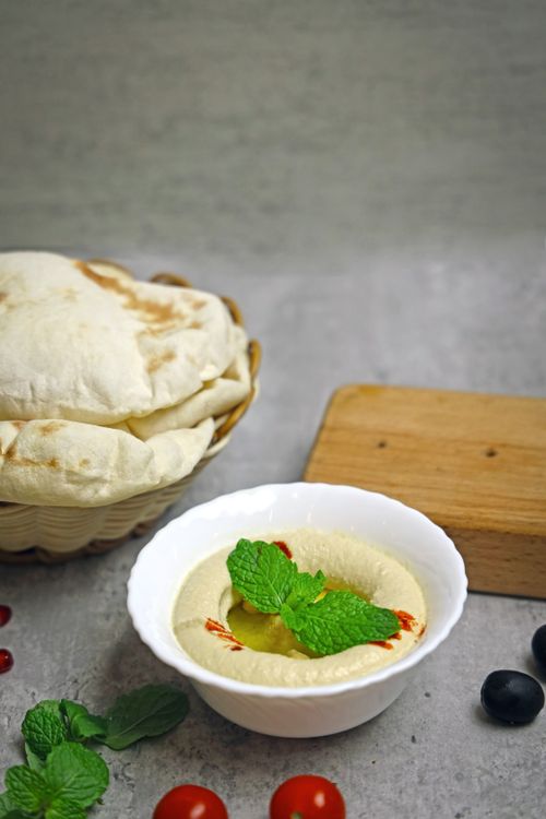 Free Delicious homemade hummus garnished with mint leaves, served with pita bread. Stock Photo