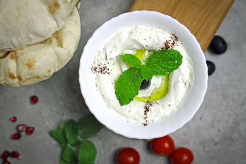 Free Creamy Greek yogurt dip garnished with mint and olive, perfect for a healthy snack. Stock Photo