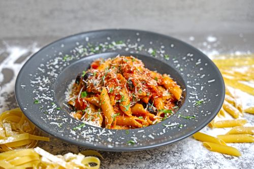 Free Savory penne pasta with rich tomato sauce, garnished with cheese and herbs. Stock Photo