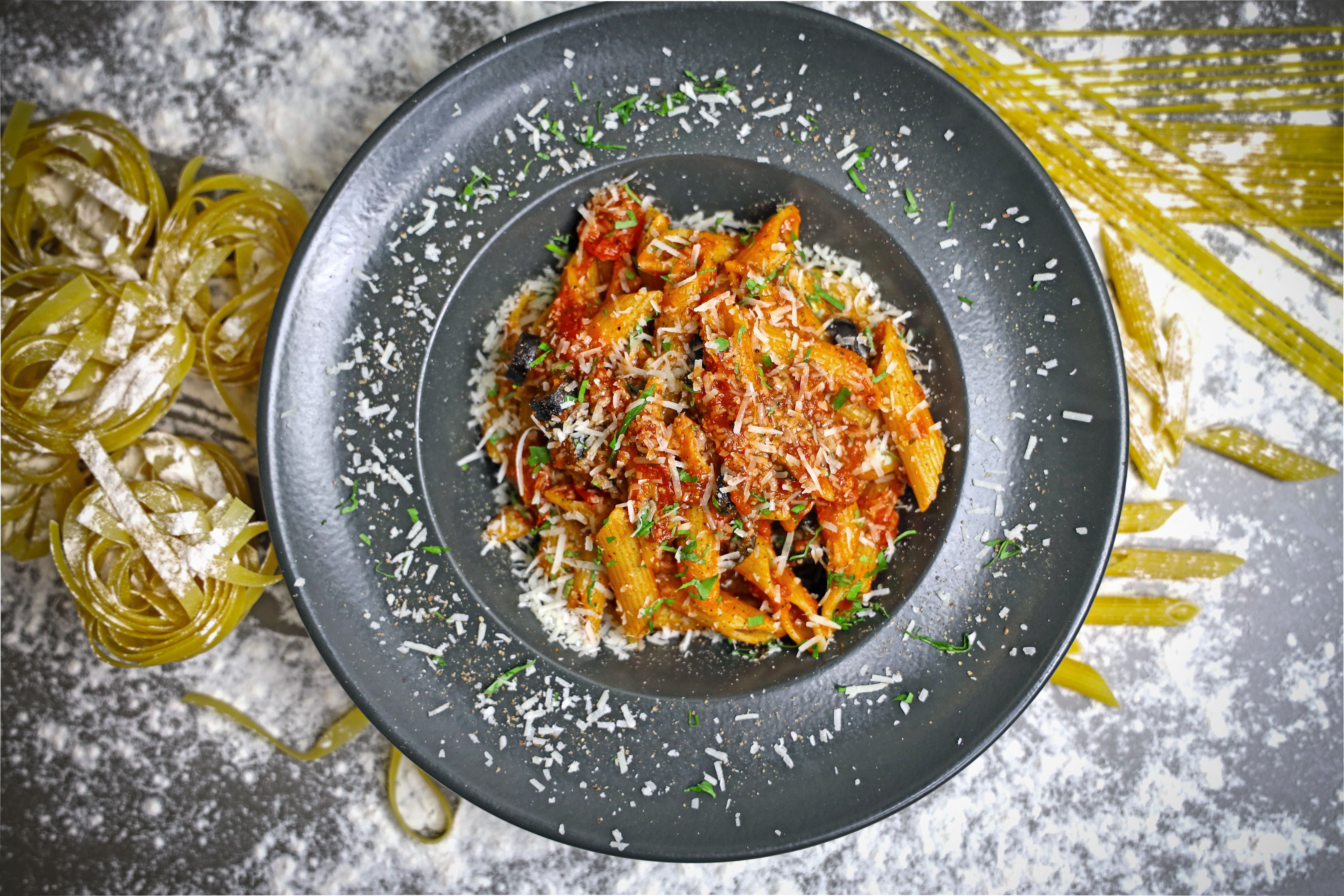 Top-down view of vibrant Italian pasta with tomato sauce on a black plate. Top-down view of vibrant Italian pasta with tomato sauce on a black plate.