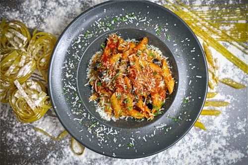 Free Top-down view of vibrant Italian pasta with tomato sauce on a black plate. Stock Photo