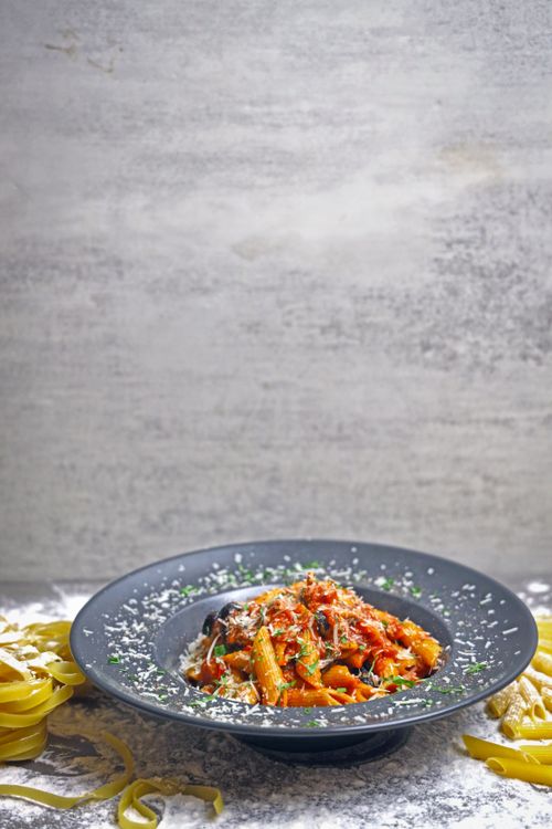 Free Delicious gourmet pasta with a tomato-based sauce and herbs on a rustic plate. Stock Photo