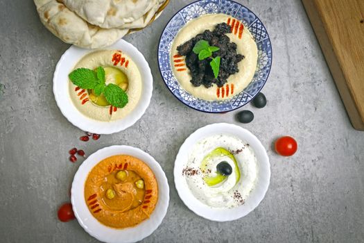A delicious array of Middle Eastern dips including hummus, baba ghanoush, and labneh served with flatbread.