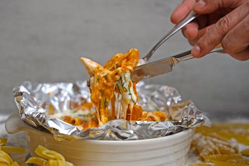 A person is holding a fork over a bowl of pasta