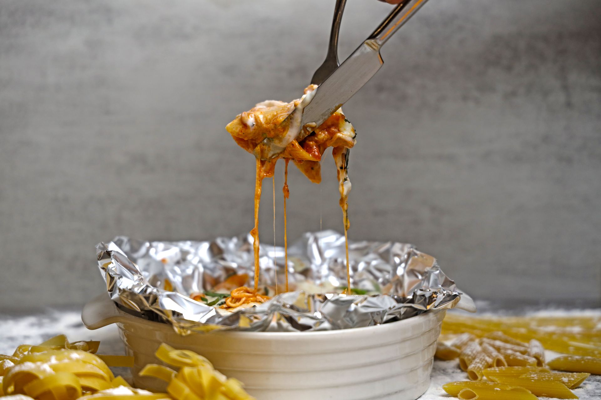 Close-up of cheesy pasta in a foil-lined ceramic bowl, freshly baked and mouth-watering.