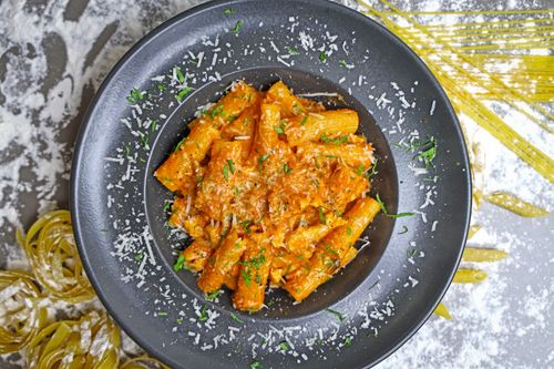 Free Tasty rigatoni topped with tomato sauce and herbs, captured on a black plate with cheese. Stock Photo