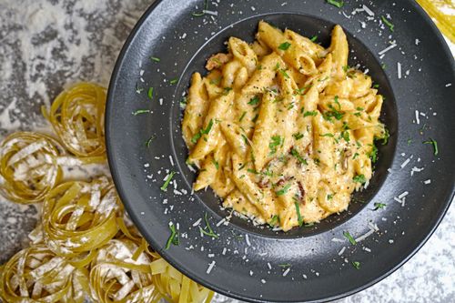 Free Delicious creamy penne pasta garnished with cheese and parsley. Stock Photo