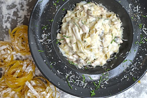 Free A bowl of pasta with chicken and cheese on top Stock Photo