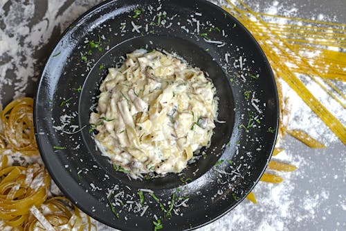 Free A black plate with pasta and parmesan cheese Stock Photo