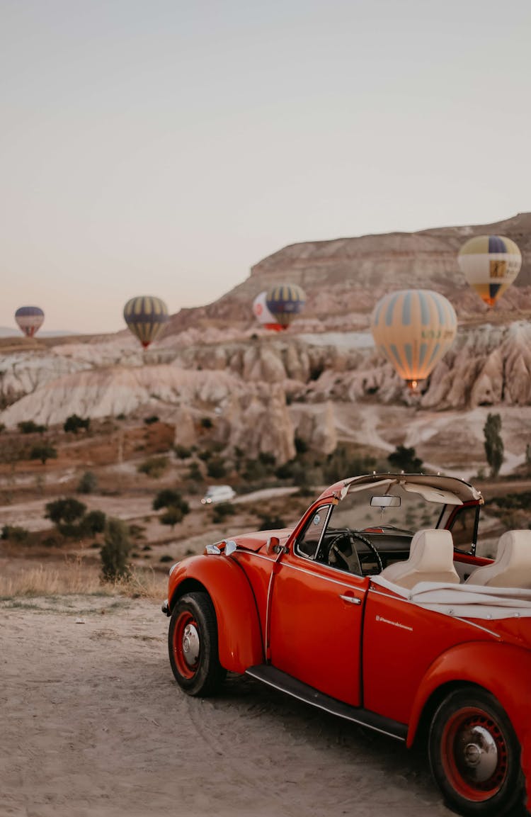 Red Convertible Car Parked Near Hot Air Balloons 