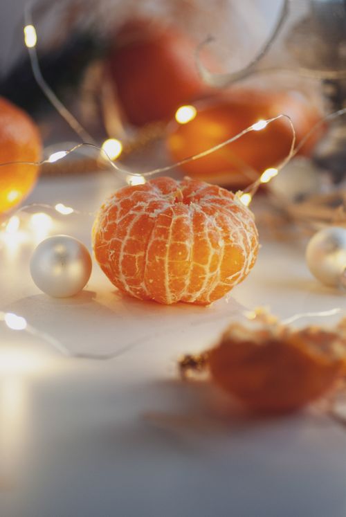 Free A peeled mandarin surrounded by festive lights and decorations evokes a warm holiday atmosphere. Stock Photo