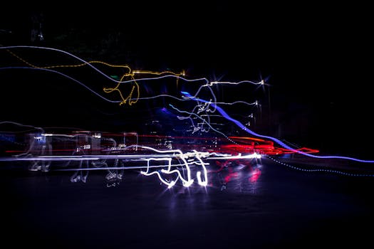 Long exposure capture of vibrant light trails creating abstract patterns in an urban nightscape.