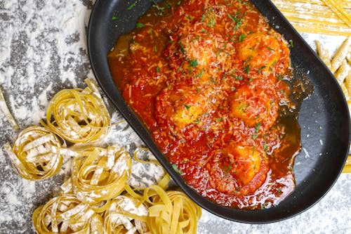 Meatball Sauce on Oval Cast Iron Beside Tagliatelle Pasta