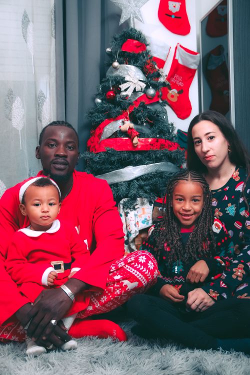 Free A family with two children enjoying Christmas by a decorated tree indoors. Stock Photo