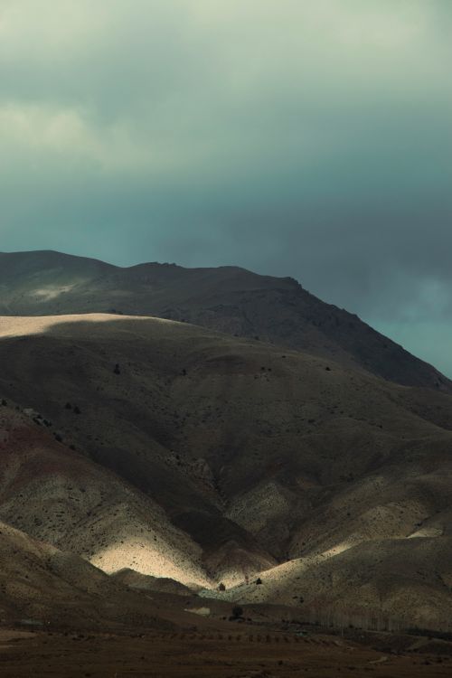 Free A captivating view of brown mountains under moody cloud cover, emphasizing geological formations. Stock Photo