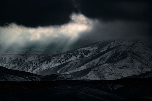 Free Snow-covered mountains under dramatic lighting in Mashhad, Iran, capturing the essence of winter. Stock Photo