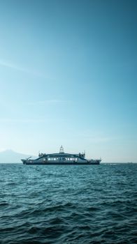 A scenic view of a ferry cruising on the Aegean Sea under a clear blue sky in İzmir, Turkey.