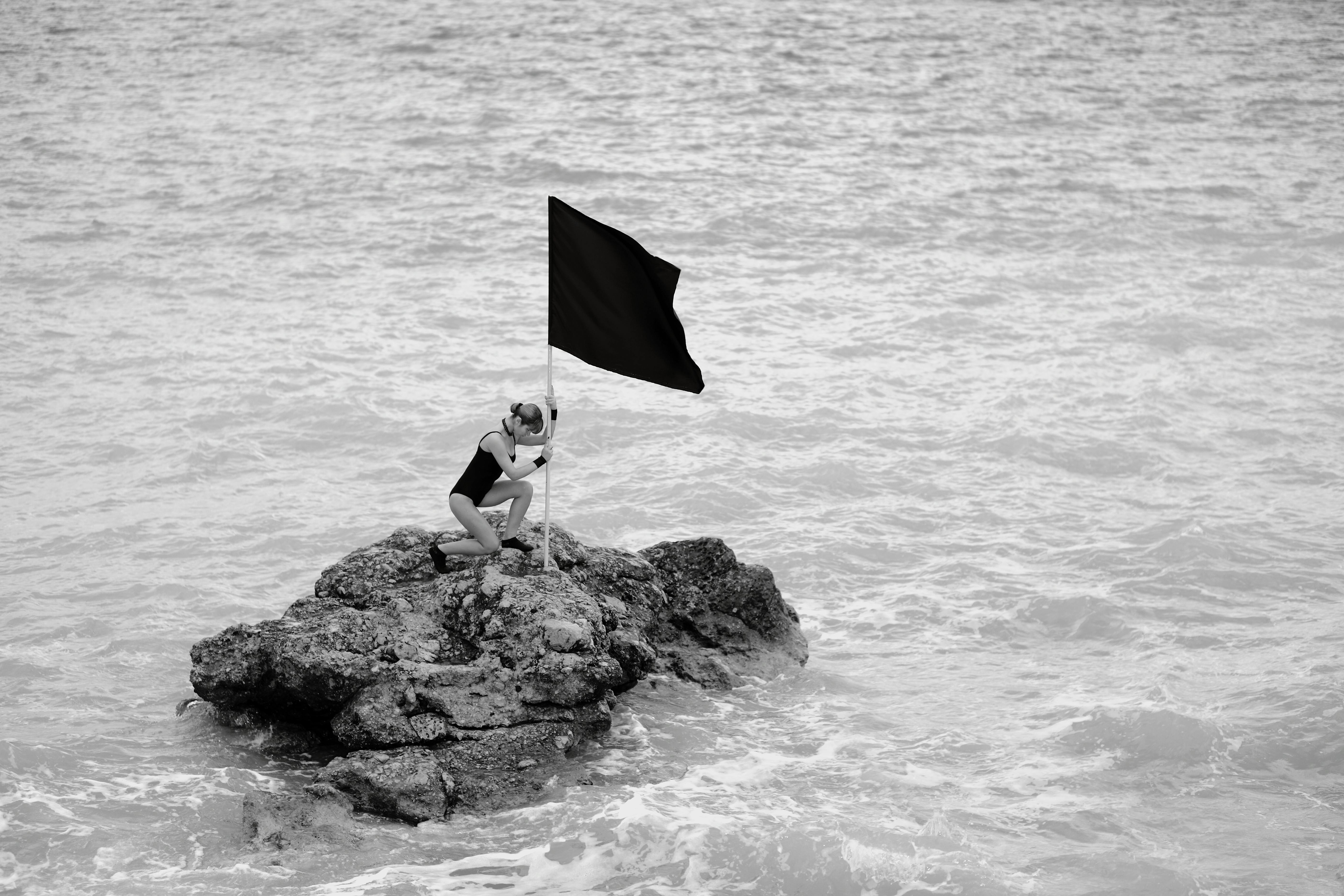 woman on rock formation holding a flag