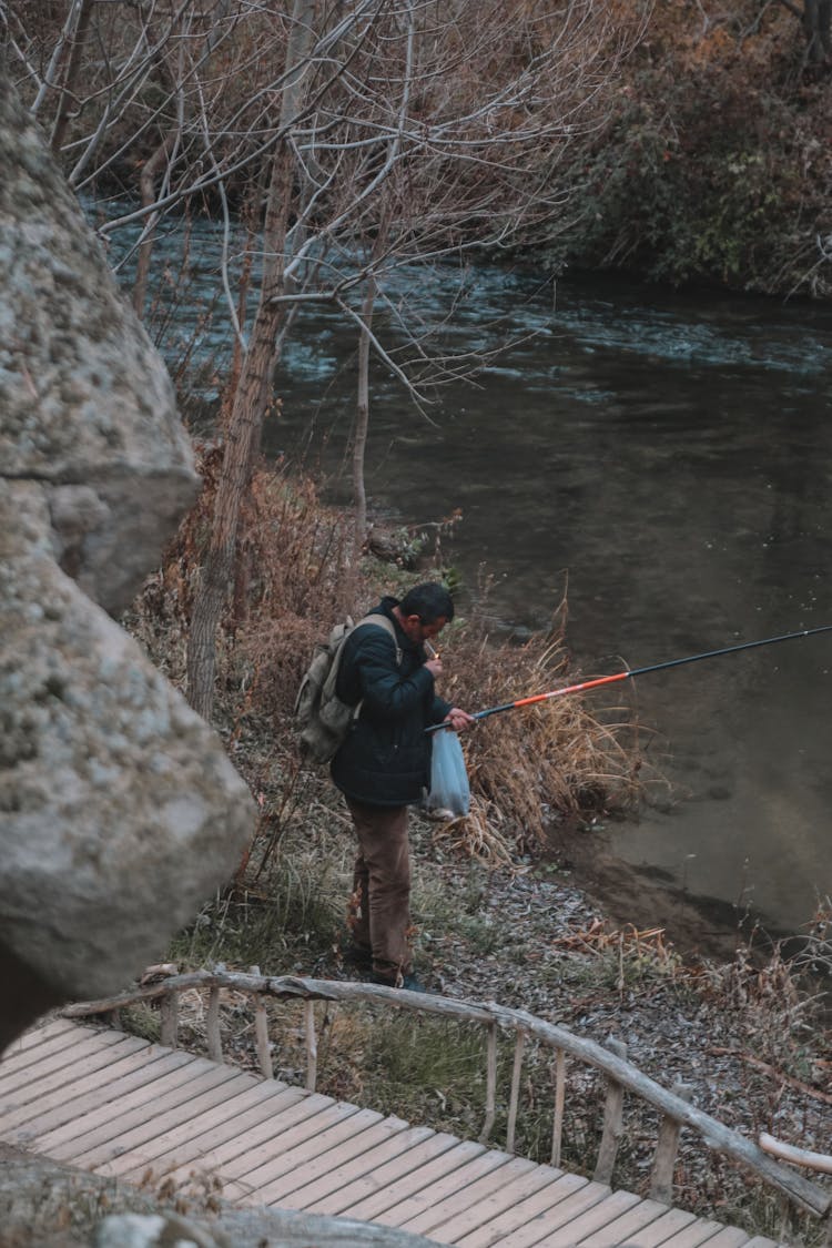 Photograph Of A Man With A Black And Orange Fishing Pole