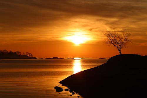 View of a Silhouetted Hill near a Body of Water at Sunset