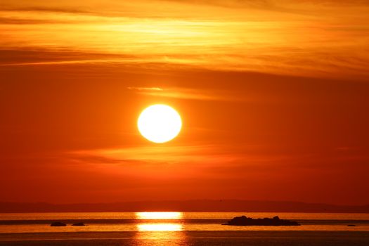 Stunning sunset with orange hues over a tranquil ocean view, capturing serene beauty.