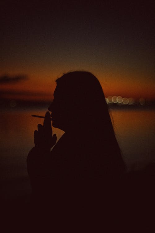 Free A Silhouette of a Person Smoking a Cigarette Stock Photo