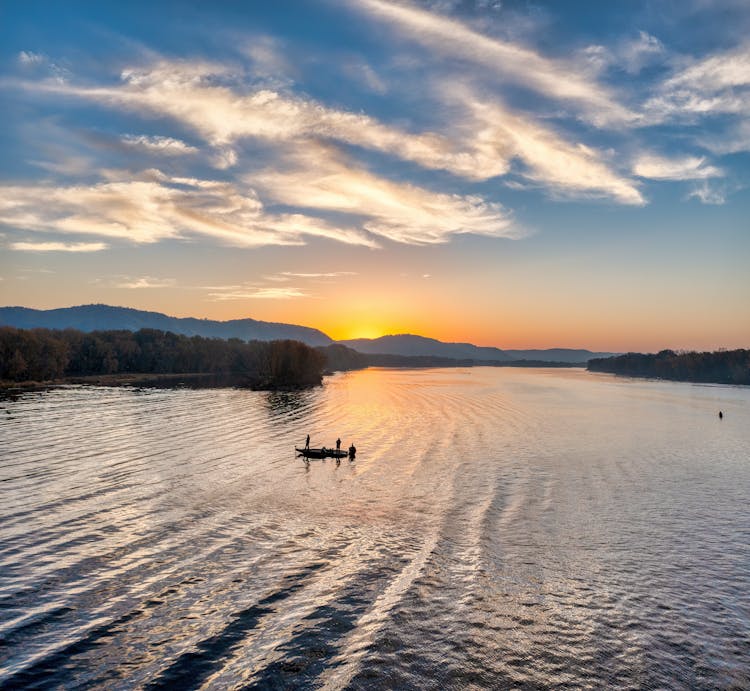 Silhouette Of A Boat Sailing On The Lake During Golden Hour 