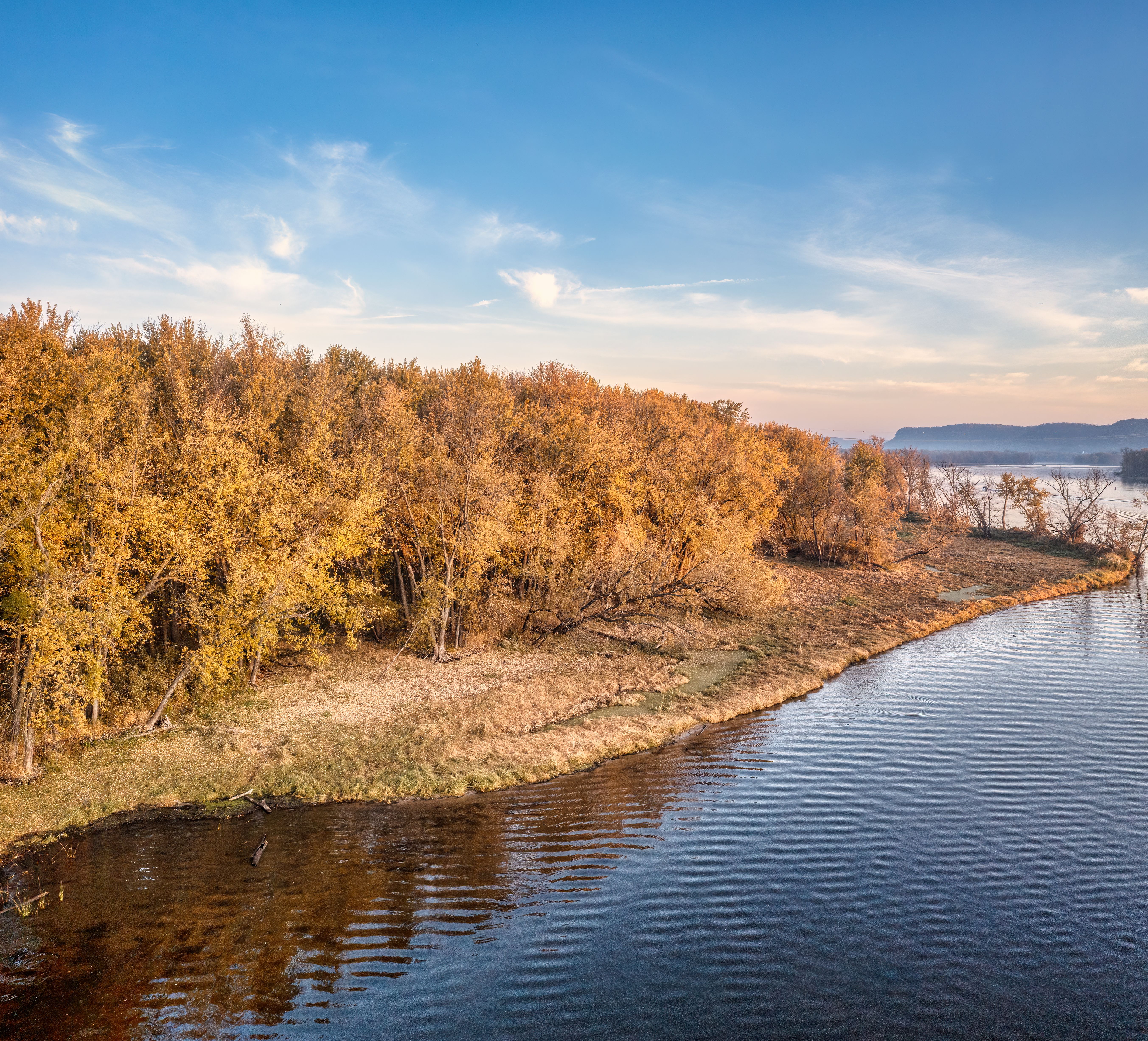 Breathtaking aerial view of golden autumn trees lining a calm lake in West Newton, MN.