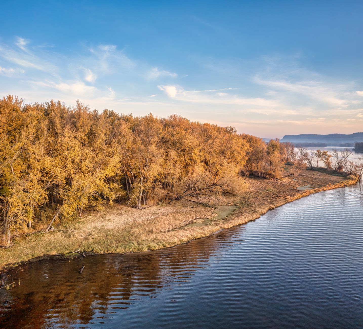 Breathtaking aerial view of golden autumn trees lining a calm lake in West Newton, MN.