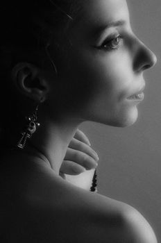Black and white portrait of a woman in profile wearing unique earrings, showcasing elegance and style.