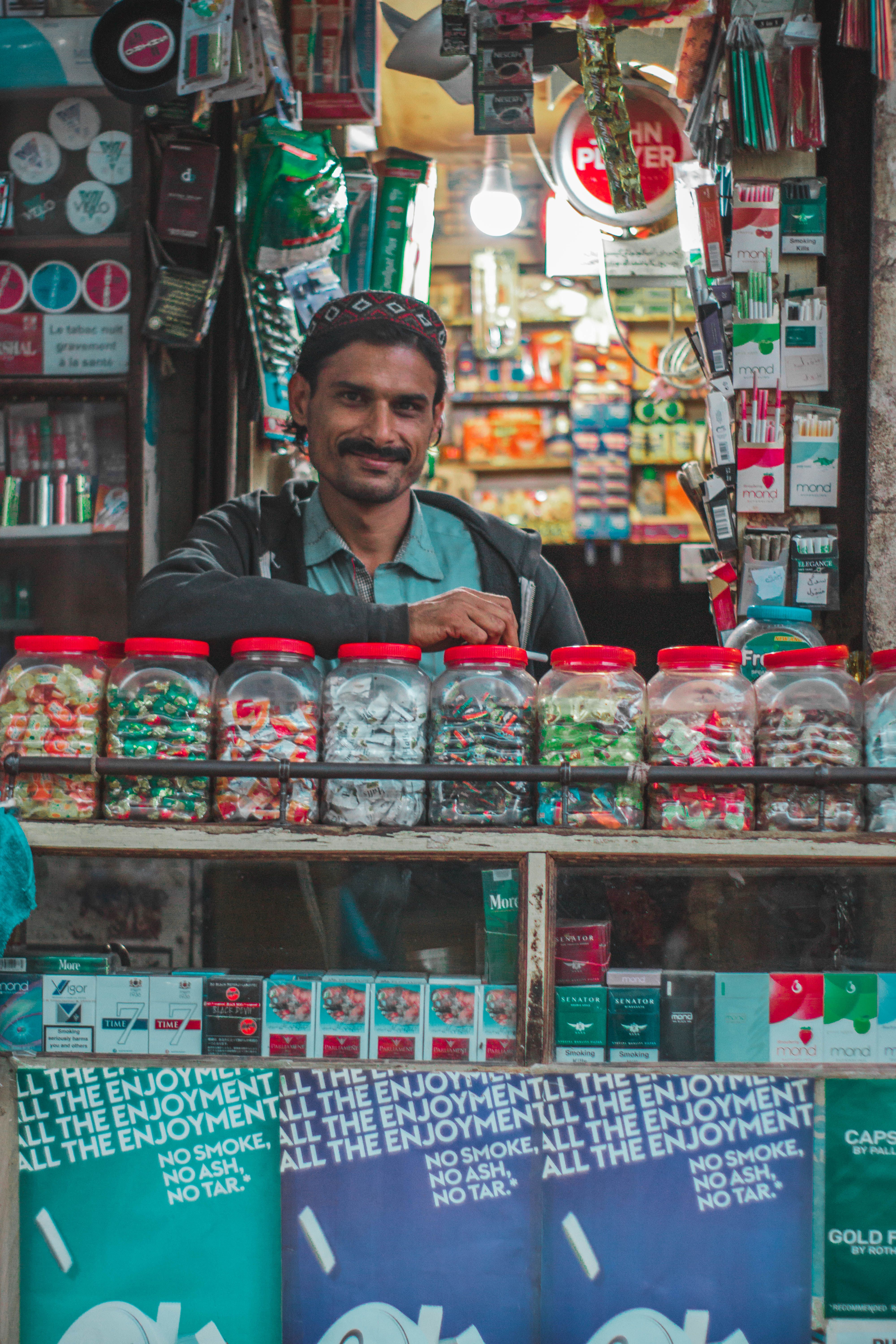 A shopkeeper at his counter, jars of stock in front of him