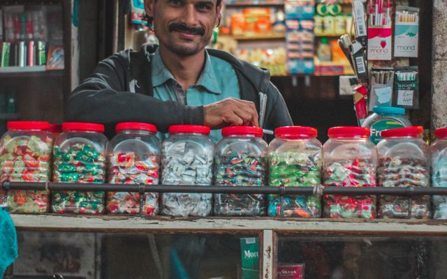 A shopkeeper at his counter, jars of stock in front of him
