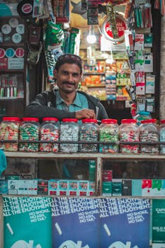 A street vendor with candy jars and products in a vibrant urban market setting.