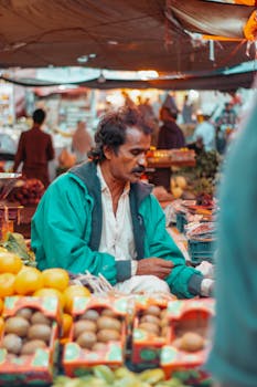 A vendor at an outdoor market surrounded by fresh produce and colorful fruits.