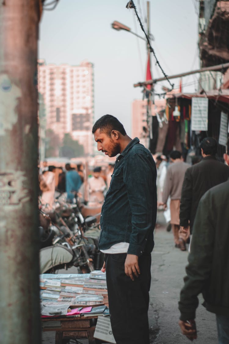 Man Buying Book On Stand On Street Market