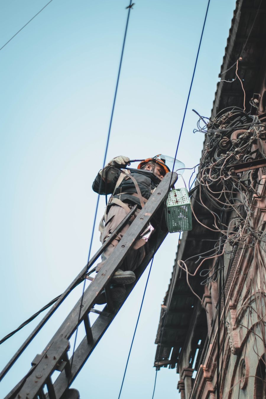 Électricien sur une échelle travaillant sur des câbles extérieurs