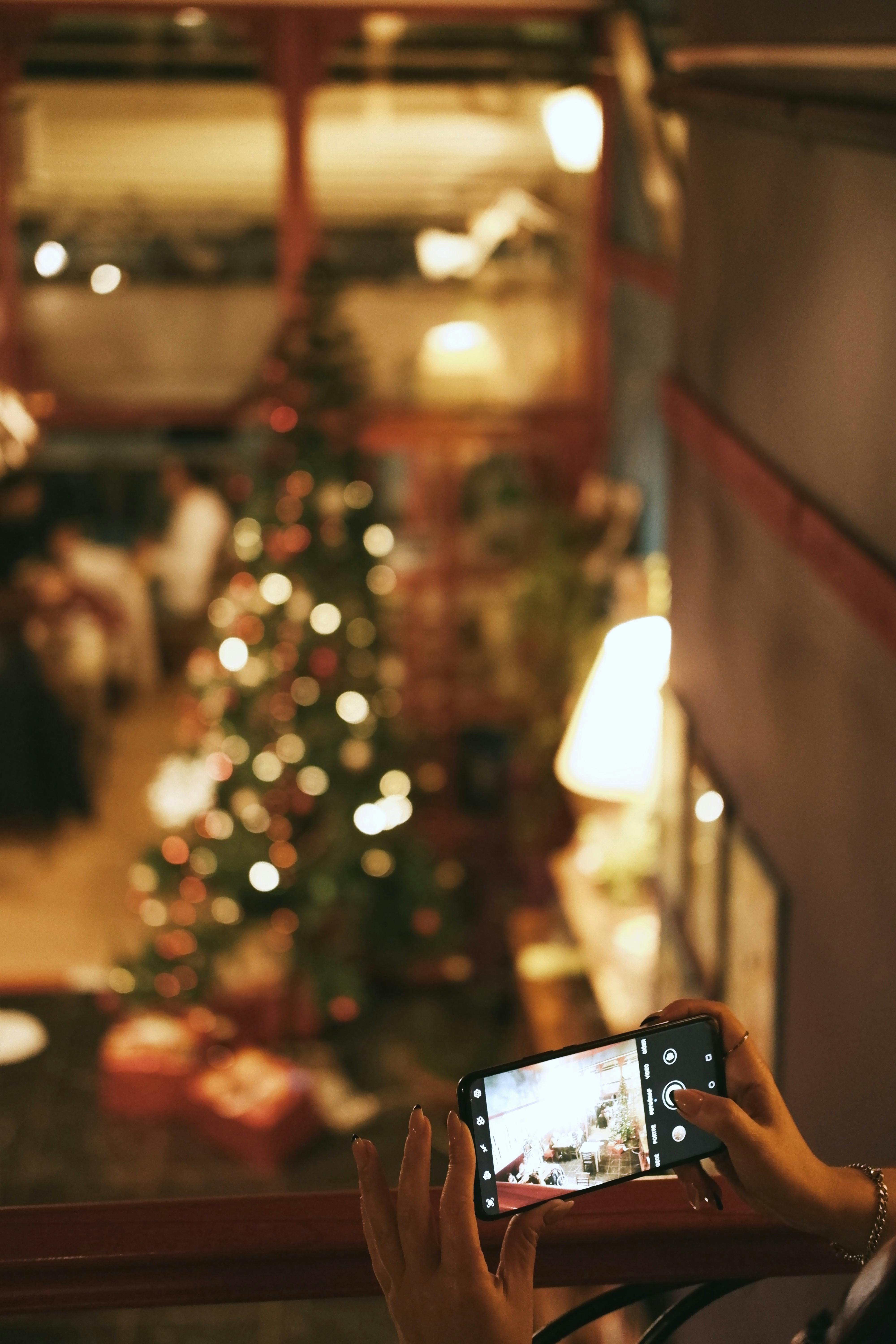 Free A smartphone capturing a beautifully decorated Christmas tree indoors. Stock Photo