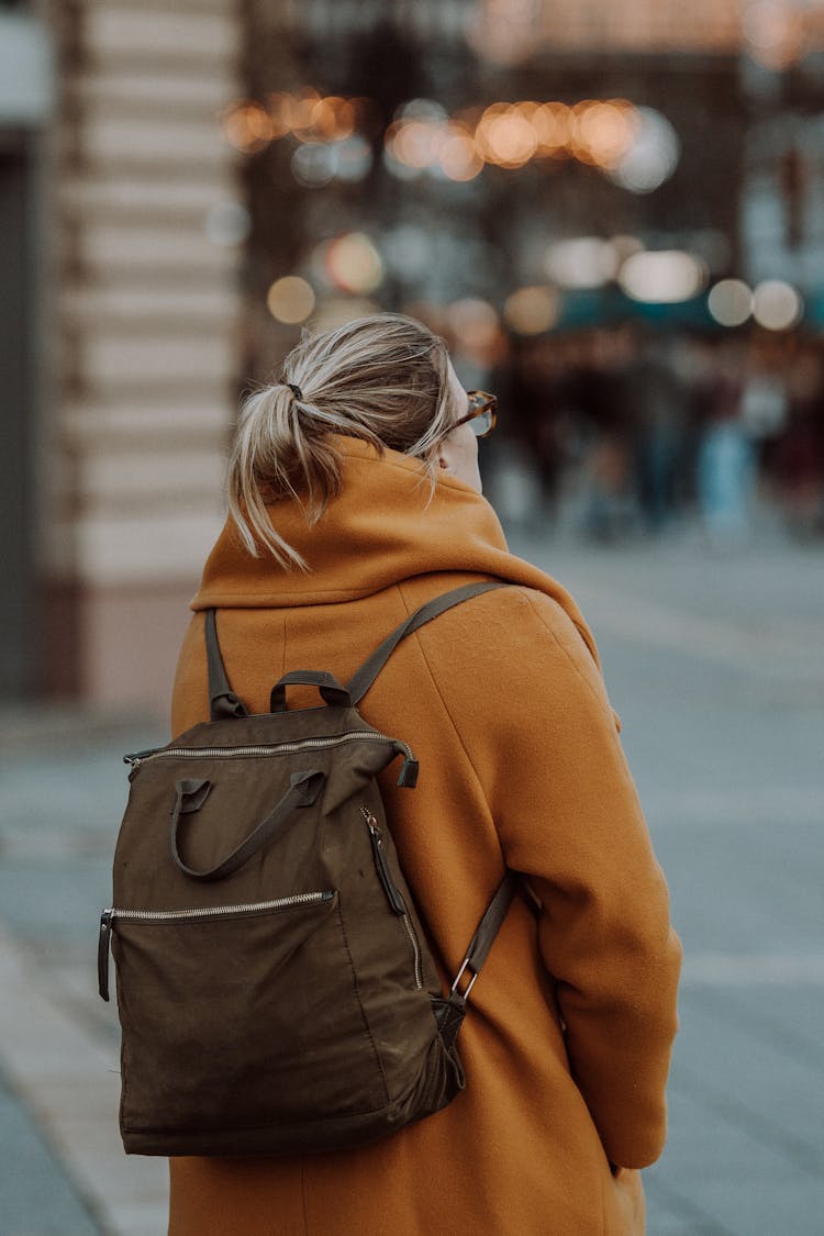 Woman In Coat With Backpack In City