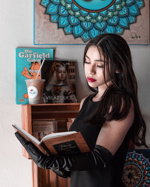 Free Woman in black dress reading a book in an artful room with colorful decor and bookshelves. Stock Photo