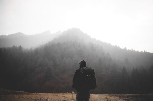 Free Silhouette of a hiker with a backpack facing misty mountains on an outdoor adventure. Stock Photo