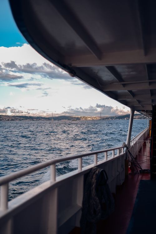 Free A serene view from a ferry deck showcasing the ocean and distant coastline under a bright sky. Stock Photo
