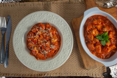 Free Top view of gnocchi in tomato sauce on plate and bowl. Perfect Italian meal setting. Stock Photo