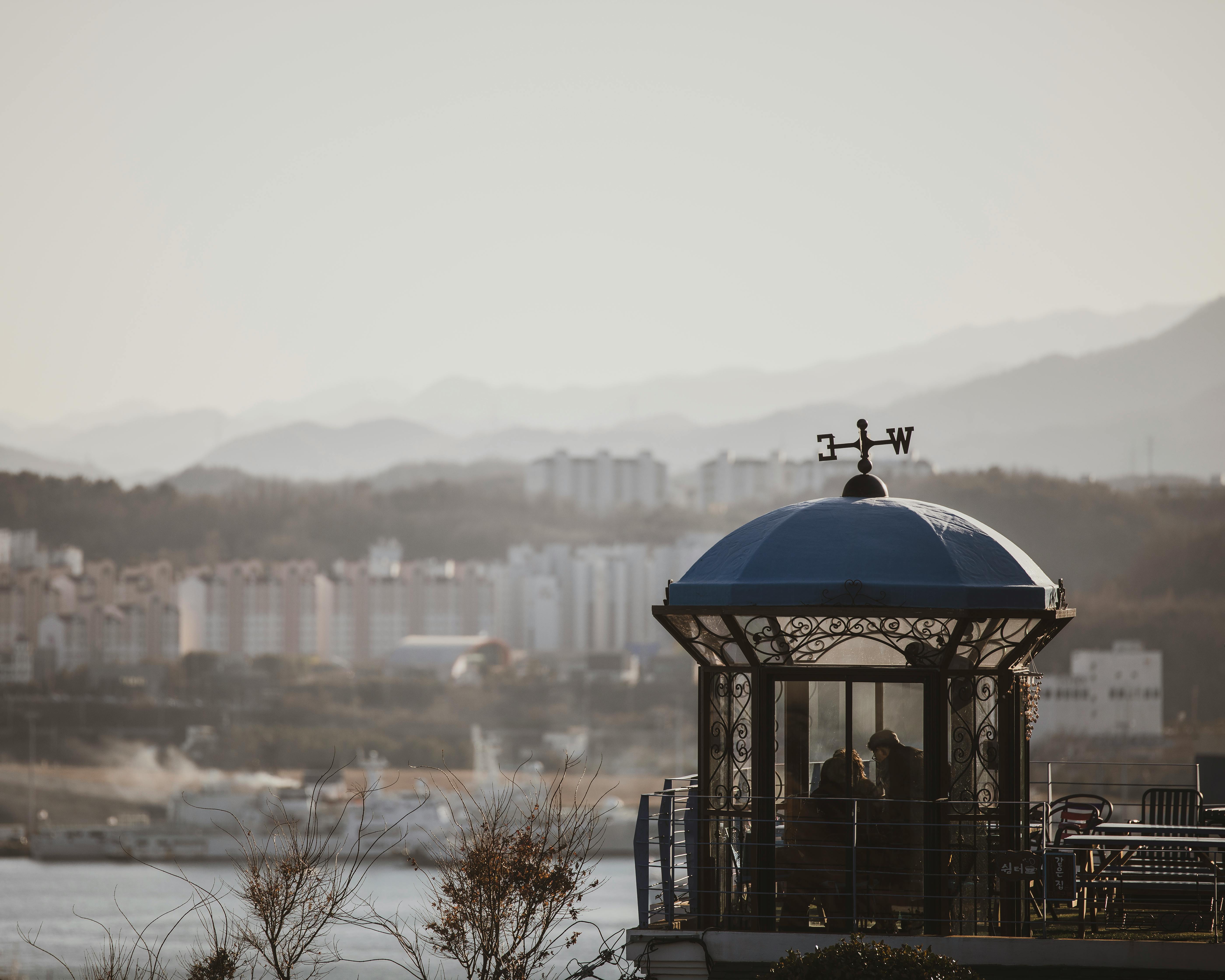 Pavilion with a blue dome overlooking Donghae city with mountains in the background.
