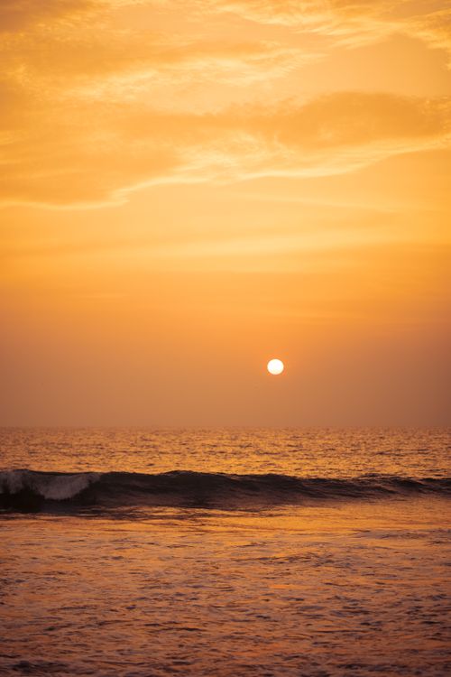 Free A mesmerizing view of the golden sunset casting reflections on the ocean waves. Stock Photo