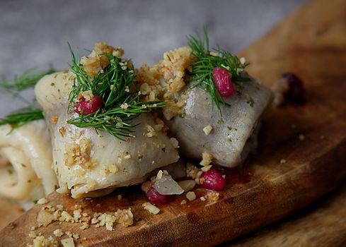 Savory stuffed cabbage rolls garnished with pomegranate and dill on a wooden board.