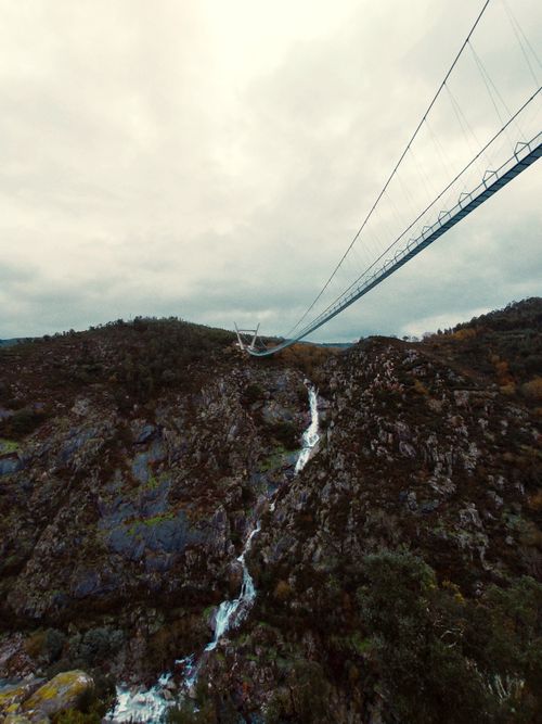 Free A breathtaking view of the Arouca suspension bridge spanning rocky terrain under an overcast sky. Stock Photo