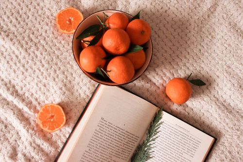Free A warm and inviting indoor scene featuring a bowl of fresh mandarins with an open book, perfect for cozy reading. Stock Photo