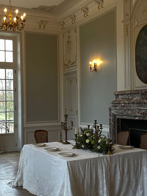 A beautifully decorated vintage dining room with an ornate chandelier and fireplace setting.