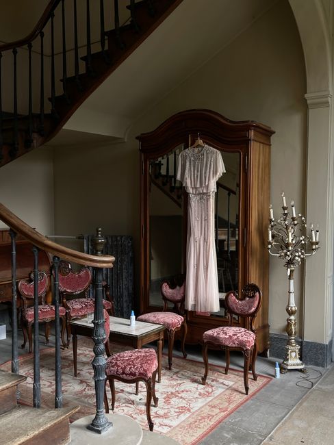 A vintage interior featuring a wooden wardrobe, elegant chairs, and classic staircase.